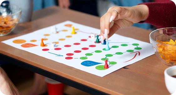 Mensen spelen een kleurrijk bordspel met pionnen en snacks op tafel.