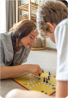 Een meisje verplaatst een groen speelstuk tijdens een bordspel met haar jongere broer.