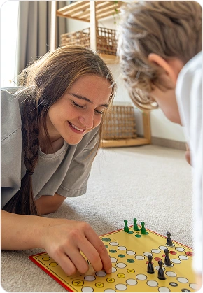 Een meisje en een jongen spelen samen een bordspel op de vloer in de woonkamer.